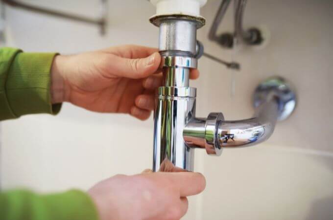 plumber-inspecting-pipe-below-sink